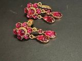 deux paires de boucles d'oreilles roses et dorées posées sur un fond noir