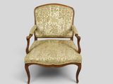 une chaise ancienne dont le dossier et les accoudoirs sont recouverts d'un tissu à motifs floraux