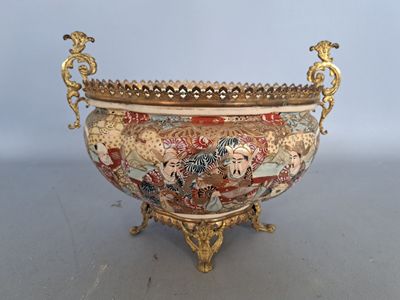 un grand bol décoré, muni d'une anse dorée, posé sur une table