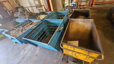 de nombreux bacs remplis de bois dans un entrepôt, avec un camion en arrière-plan