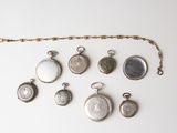 an assortment of antique pocket watches on a chain on a white surface