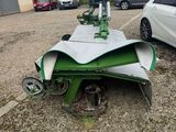 a close up of a green machine parked in a parking lot next to a white car