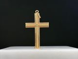 une croix dorée posée sur un socle blanc, sur fond noir
