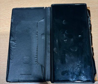 un portefeuille noir ouvert posé sur une table, à côté d'un téléphone portable