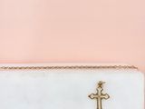 une pochette blanche ornée d'une croix dorée sur le devant