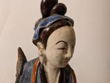 a small statue of a woman sitting on a stool