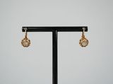 a pair of earrings on a black stand with a white background