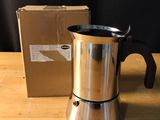 a coffee pot sitting on a table next to a box