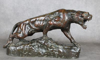 statue en bronze représentant un lion sur un rocher, la gueule ouverte