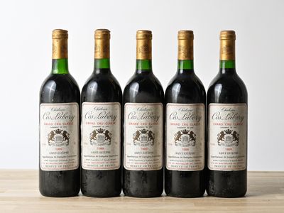 four bottles of wine are lined up on a wooden table