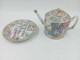 une théière et une assiette posées sur une table blanche