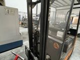 a forklift in a warehouse with a machine in the background