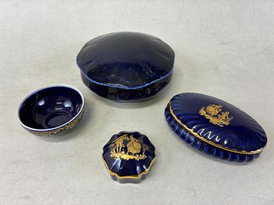 quatre objets en verre bleu ornés de motifs dorés posés sur une table