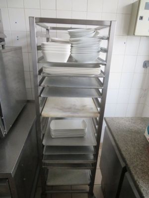 Plusieurs plateaux de nourriture sont empilés sur une étagère métallique dans une cuisine