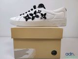 des baskets blanches ornées de fleurs noires, posées sur une boîte