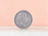 a close up of a coin with a pink background