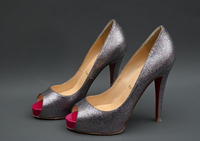 une paire d'escarpins argentés à semelles rouges sur fond gris
