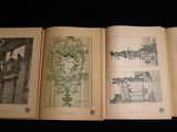 three open books on a table with drawings of buildings and trees