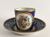 a cup and saucer on a saucer on a white table