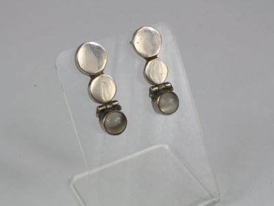 une paire de boucles d'oreilles en argent posée sur le dessus d'une vitrine transparente