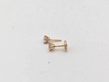 un gros plan sur une paire de boucles d'oreilles en or sur une surface blanche