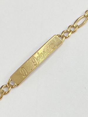 un gros plan d'un bracelet en or orné d'une plaque portant un nom