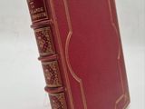 un vieux livre rouge posé sur une table à côté d'un mur blanc