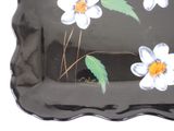 a black tray with white flowers painted on it