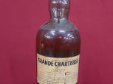une vieille bouteille de brandy repose sur une surface rouge