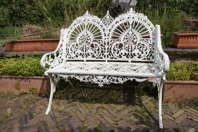 un banc blanc qui se trouve au milieu d'un jardin