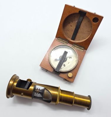 un vieux télescope en laiton dans un coffret en bois, posé sur une surface blanche
