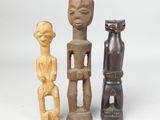 three wooden figurines of different shapes and sizes on a white surface