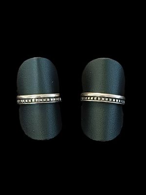 une paire de bagues en argent ornées de diamants noirs, sur fond noir