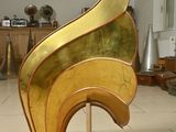 a gold sculpture on a wooden stand in the middle of a room
