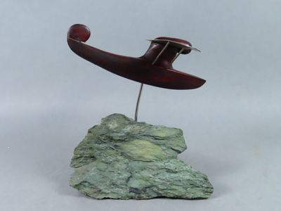 une sculpture représentant un avion posé sur un rocher, sur fond blanc