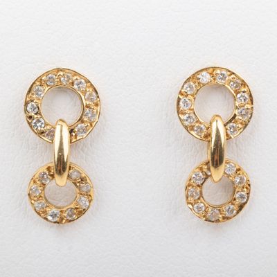 two pairs of gold earrings with diamonds on them on a white surface