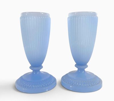 une paire de vases en verre bleu posés sur une surface blanche, sur fond blanc