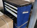 a blue workbench with drawers and a box on the floor