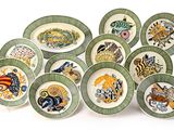 de nombreuses assiettes aux motifs variés, disposées sur un fond blanc