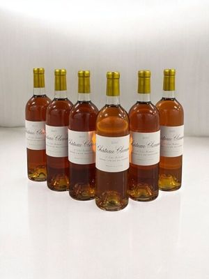 six bottles of wine are lined up in a row on a white surface