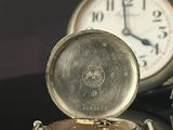 a silver pocket watch sitting on top of a black table