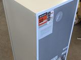 a white refrigerator sitting on the floor in a warehouse
