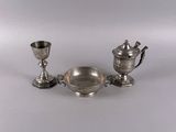 two silver cups and a saucer on a white surface