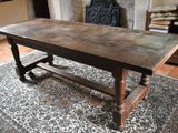 une grande table en bois posée sur un tapis devant une cheminée