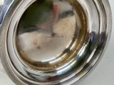 a silver plate with a silver handle on a table