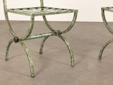 pair of antique iron chairs with green paint on them in an empty room
