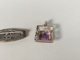 two pieces of silver and amethorate jewelry on a white surface