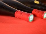 several bottles of wine are lined up on a red cloth