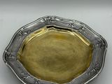 an antique silver plate with a gold rim on a white surface