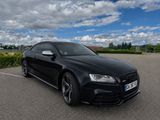 the black audi is parked in a parking lot with a cloudy sky in the background